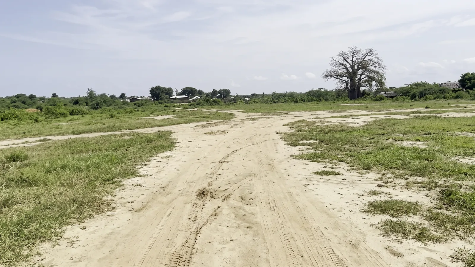 Mandhari ya kiwanja chenye nyasi na mchanga chini ya anga pana katika Mambrui 234 karibu na Sabaki
